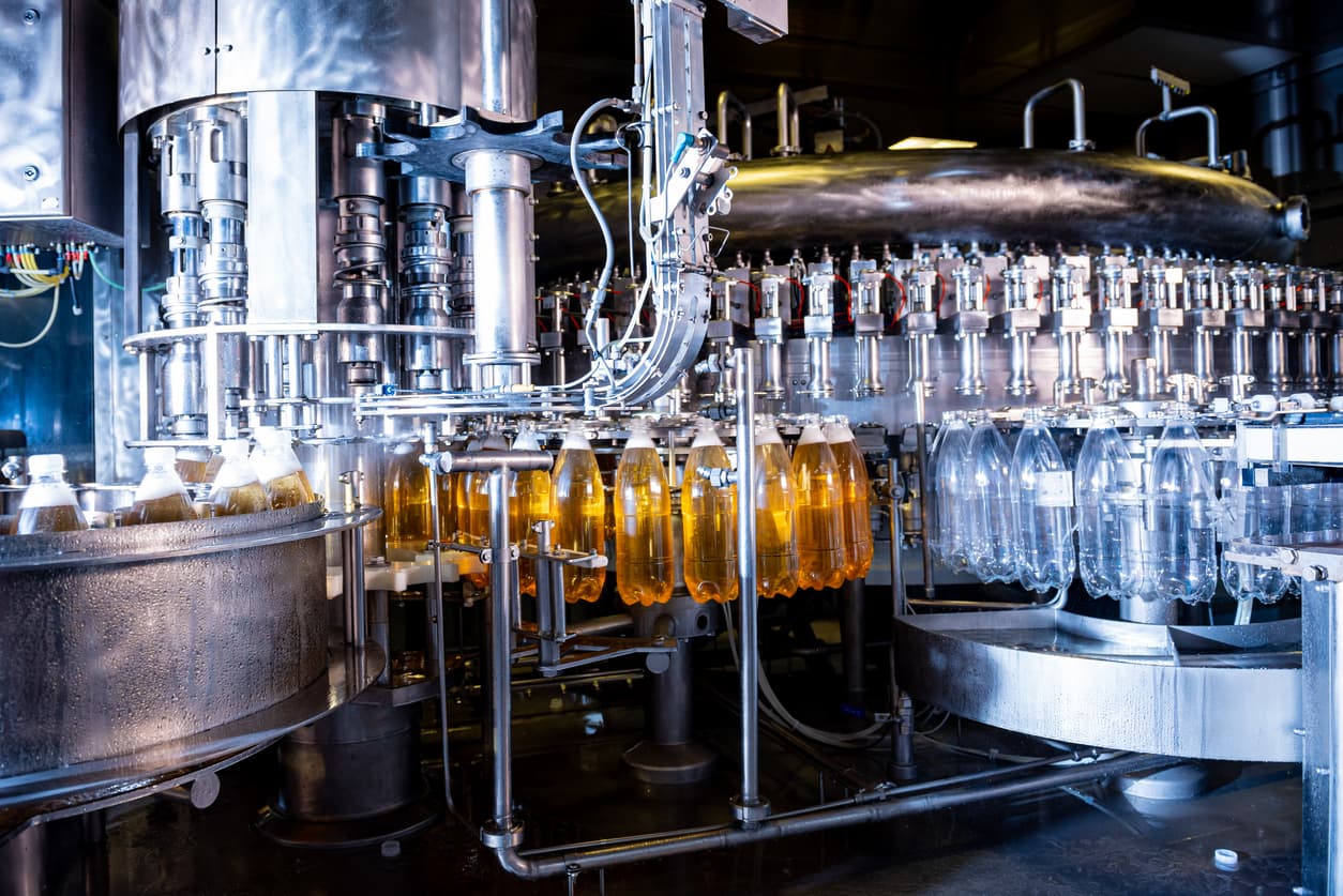 Línea de producción automatizada para el embotellado de líquidos en una planta industrial.