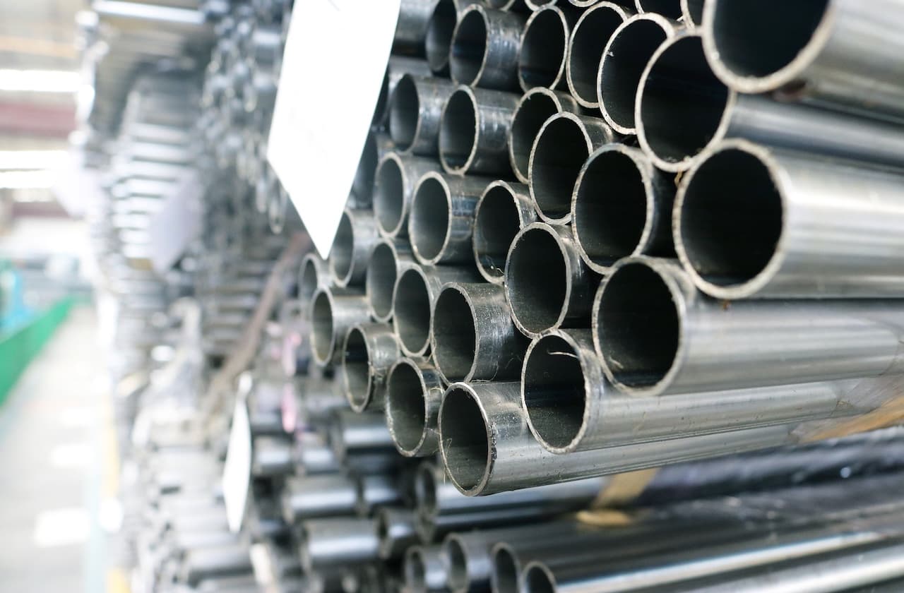 Tubería de acero inoxidable apilada en un entorno industrial, mostrando múltiples secciones cilíndricas.