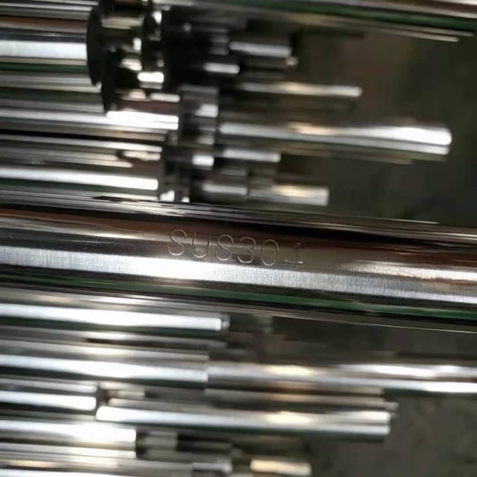 tubería de acero inoxidable con la inscripción SUS301, apilada en un entorno industrial.